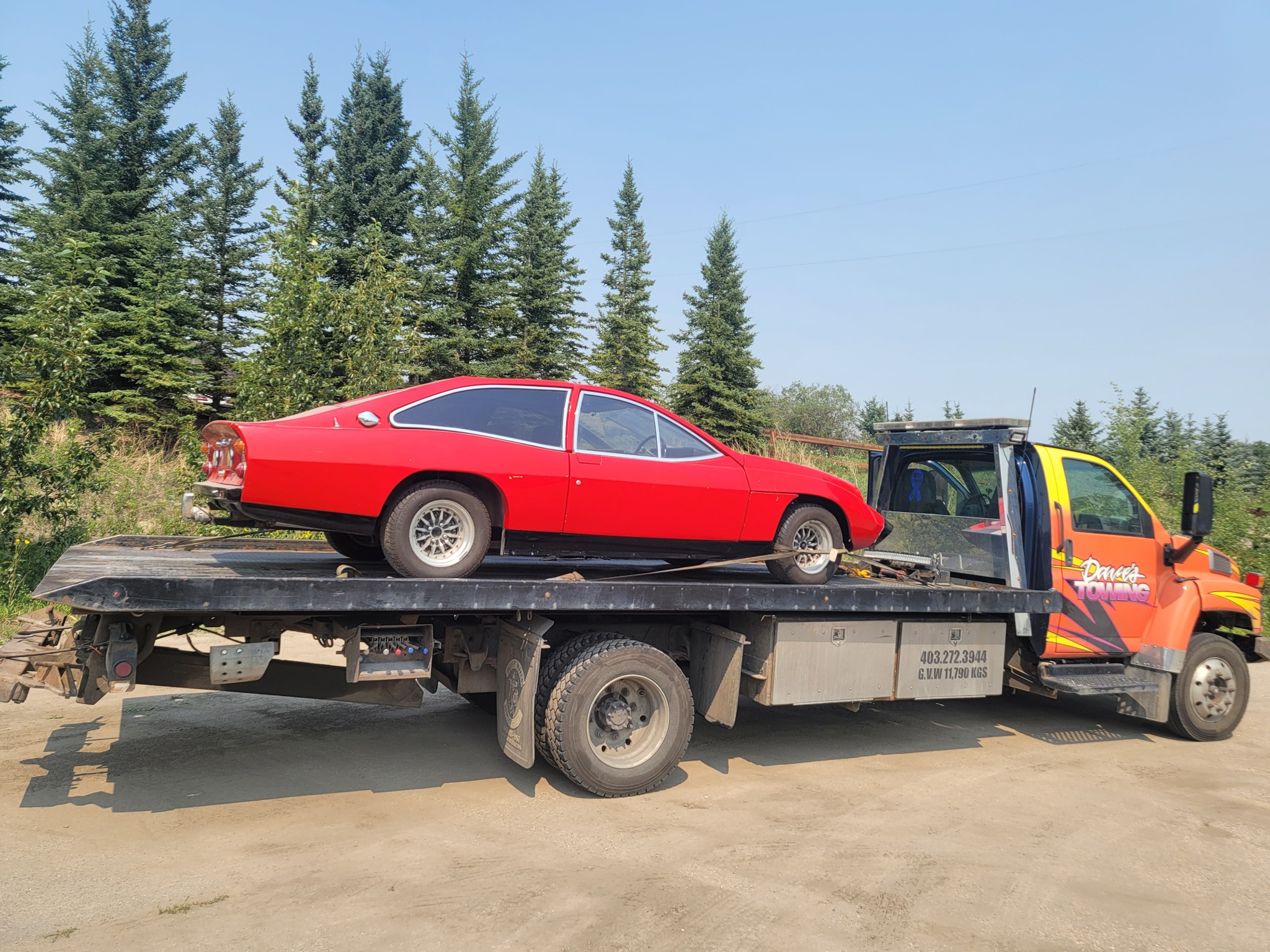 Red classic coupe loaded onto flatbed